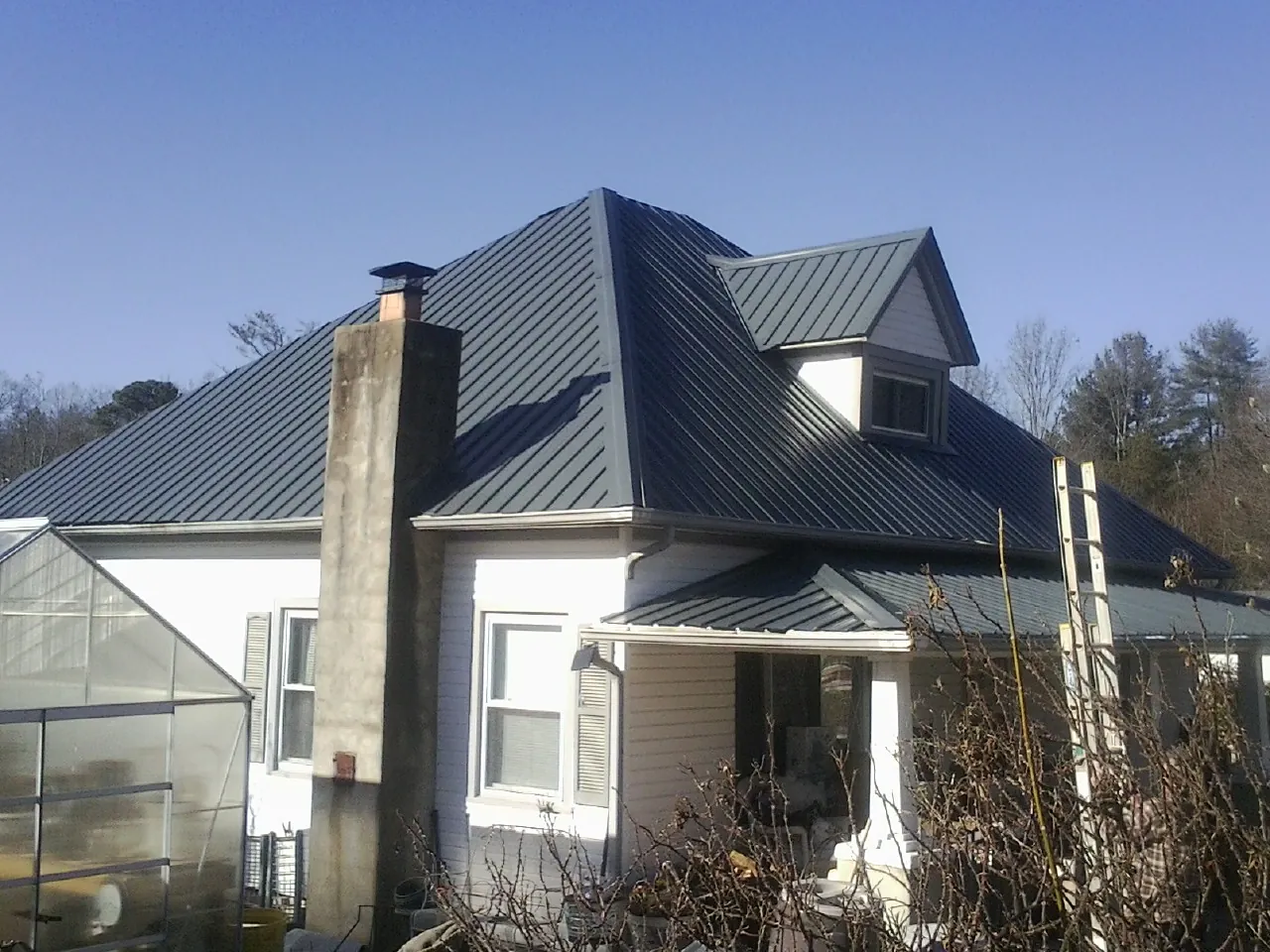 Dark blue standing seam metal roof on a white farmhouse with dormer — Slate & Tile Roof Repair by Roofing Brothers in Oil City