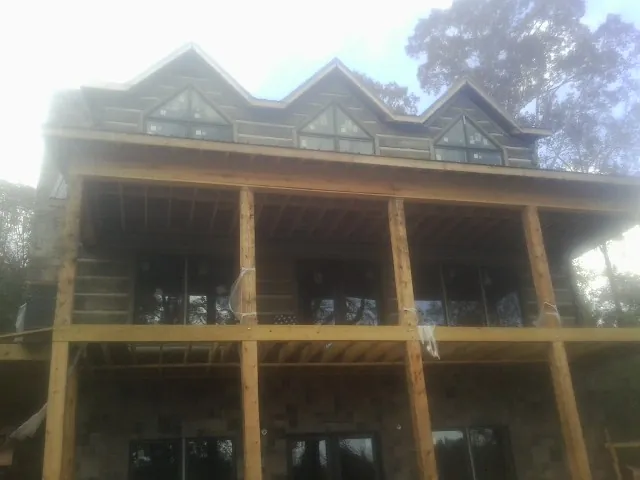 Dormers and porch framing on a large log home under construction — Roof Coating work by our crew in Oil City