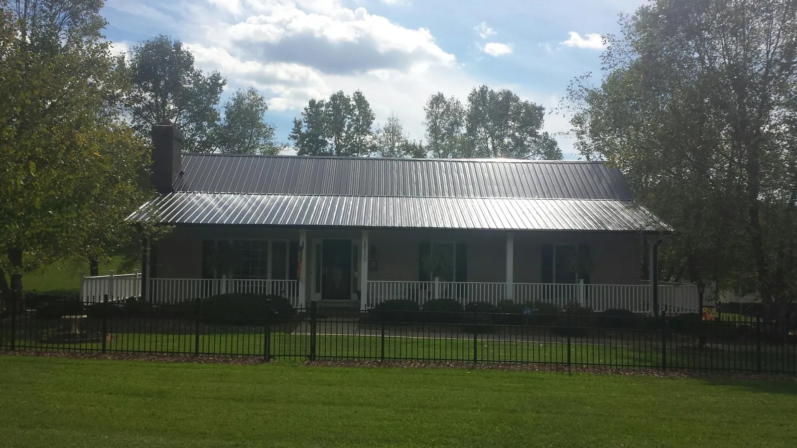 Gray metal roof on a brick ranch with a full width front porch — Gutter Guard Installation work by our crew in Oil City