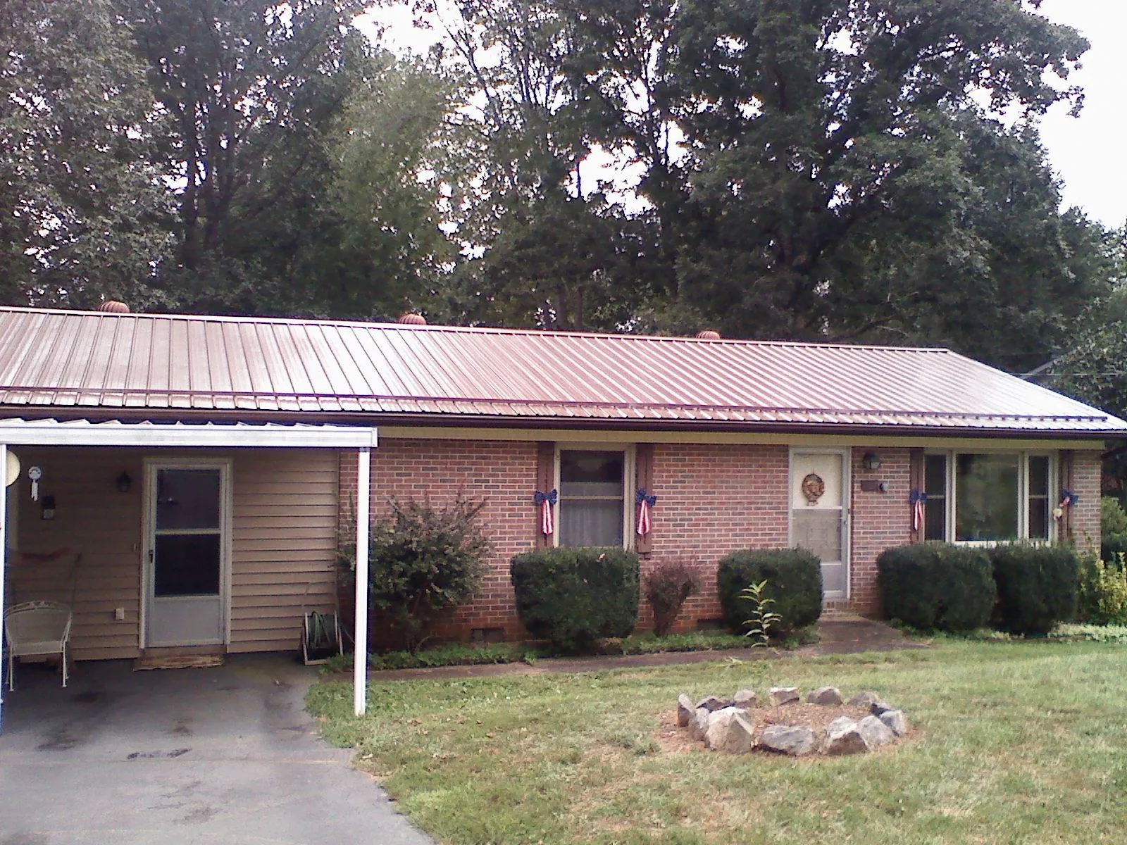 Bronze metal roof and carport on a brick ranch home — Roof Repair work by our crew in Oil City