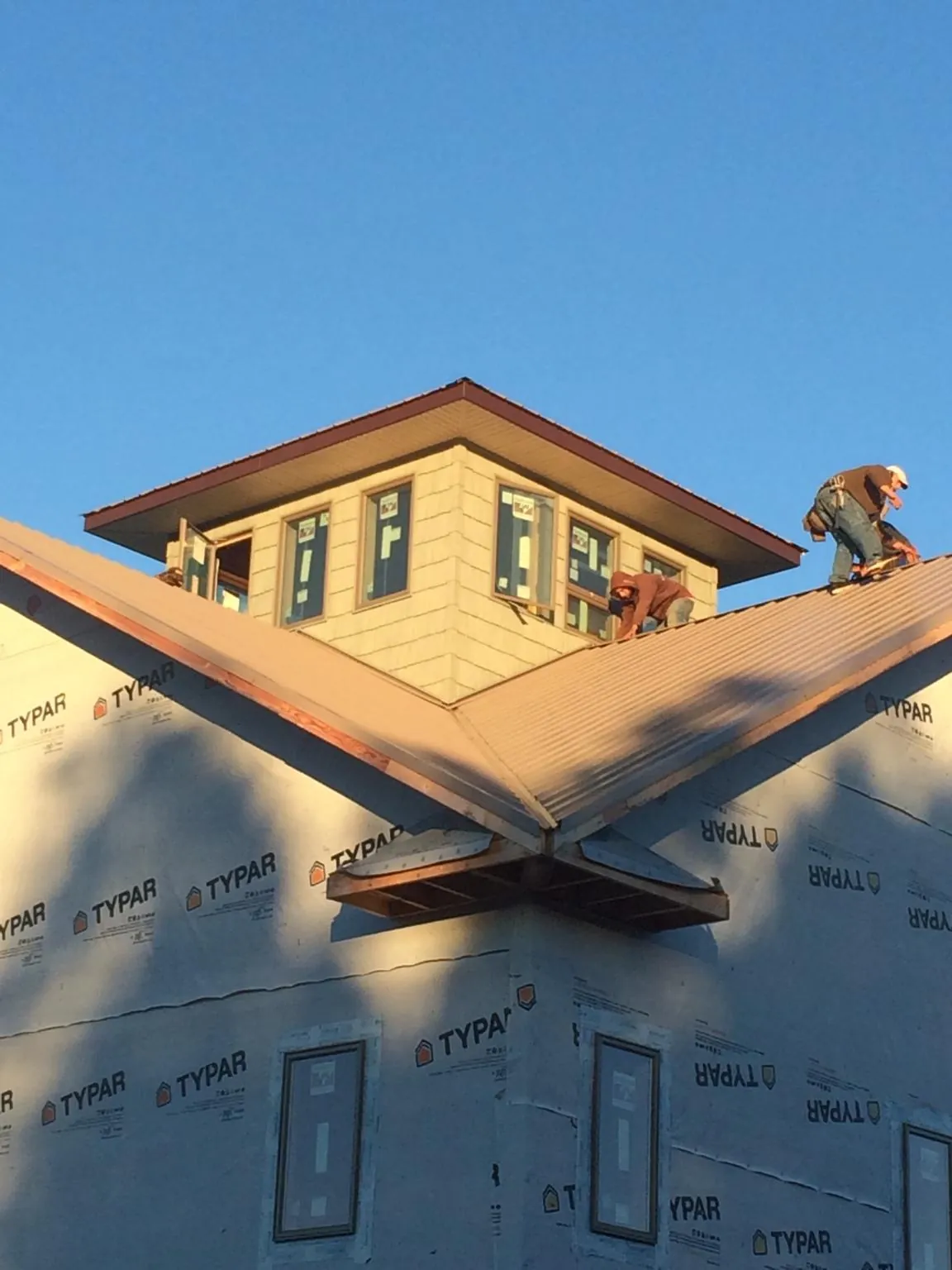 Roofers working around a rooftop cupola on a new metal roof at sunset — Roof Waterproofing in Oil City by Roofing Brothers